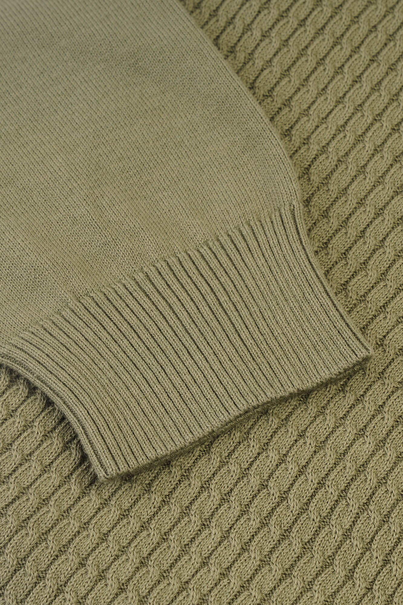 Image of Close-up of a green knitted sweater on a textured surface