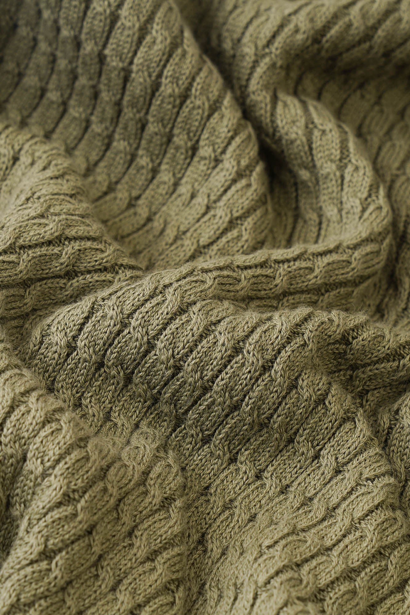Image of Close-up of a textured green fabric with a cable knit pattern